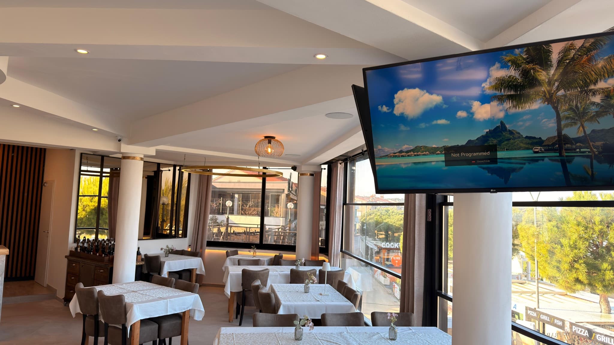 Zidno montirani televizor i ugradbena rasvjeta u prostoru restorana.